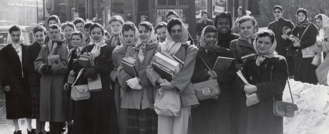 Crowd of girls stands on Dudley St., near Greenville St., Roxbury, today for bus to take them to Roxbury Memorial High School for Girls Boston schools reopened for first time since Friday.